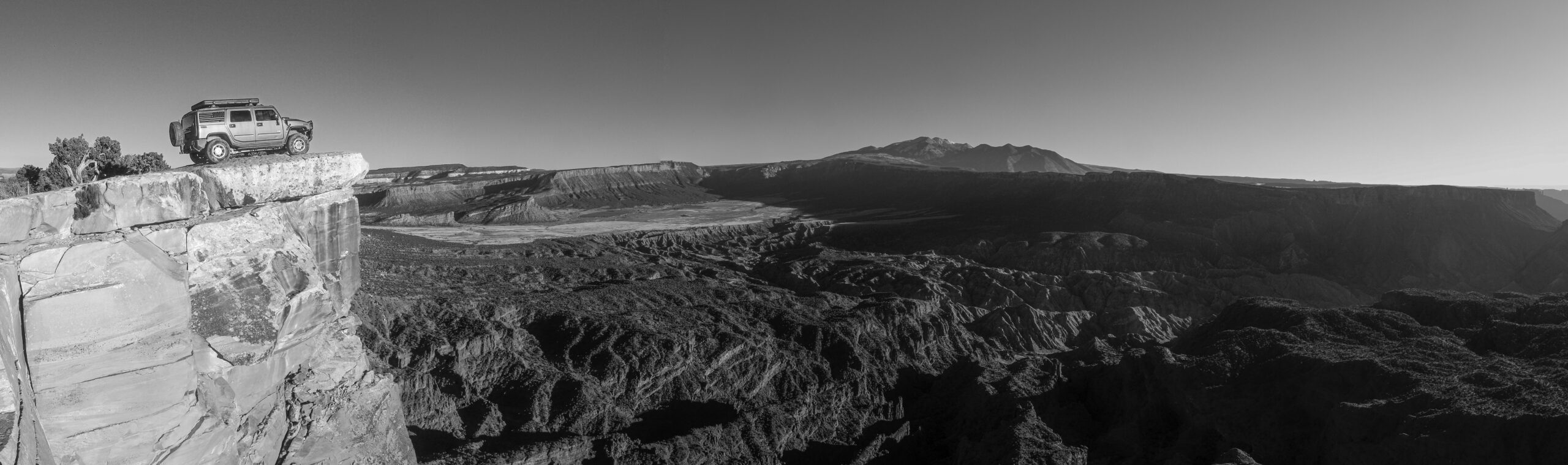 hummer h2 on the edge of a cliff overlooking the desert below.